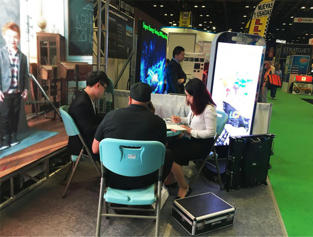 奥兰多橘城会展中心多宝电竞展位现场，外贸部经理黄勇强和何巧玲与意向客户在交谈中